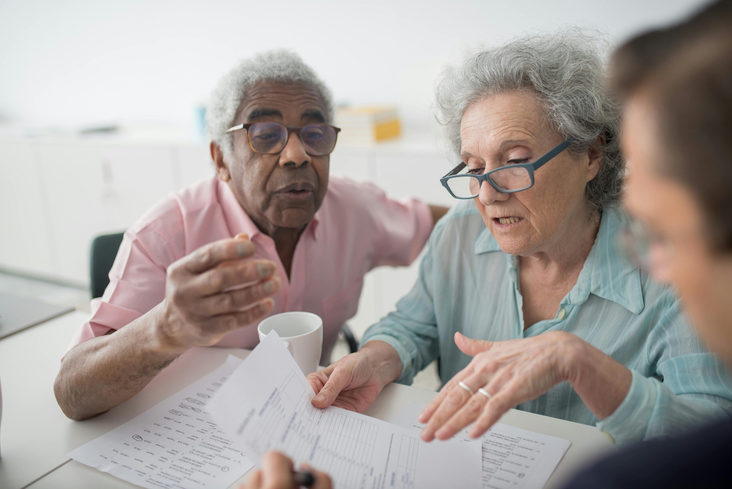Home Elderly couple discussing financial documents with a consultant in an office setting.